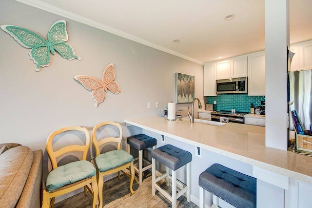 kitchen featuring white cabinets, light wood-type flooring, stainless steel appliances, sink, and kitchen peninsula