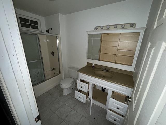 full bathroom featuring shower / bath combination with glass door, tile patterned floors, vanity, and toilet