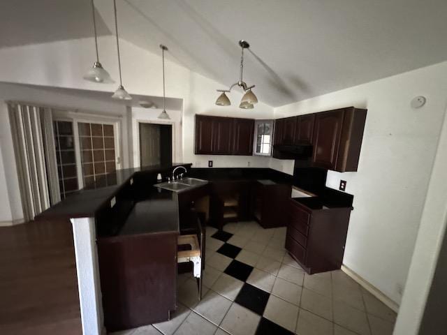 kitchen with pendant lighting, lofted ceiling, light tile patterned floors, dark brown cabinets, and kitchen peninsula