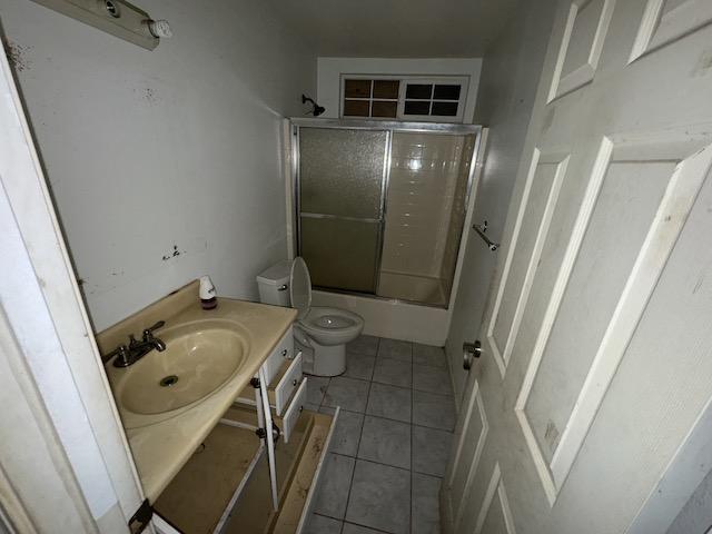 full bathroom with tile patterned flooring, vanity, combined bath / shower with glass door, and toilet