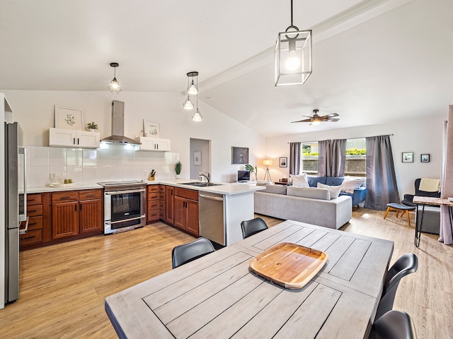 dining space featuring ceiling fan, sink, vaulted ceiling with beams, and light hardwood / wood-style floors