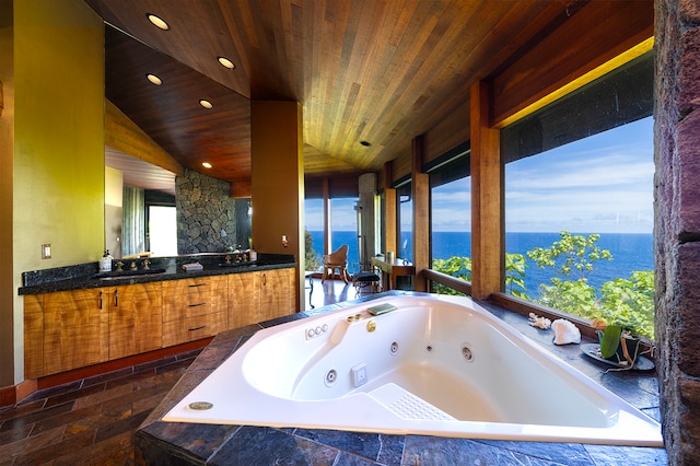 bathroom with a water view, vanity, vaulted ceiling, and tiled tub