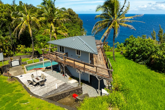 back of house featuring a yard, a pool side deck with water view, and a patio area