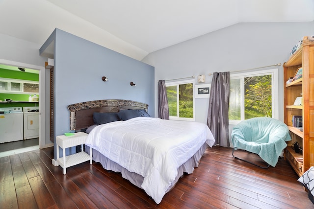 bedroom with dark wood-type flooring, vaulted ceiling, and washing machine and clothes dryer