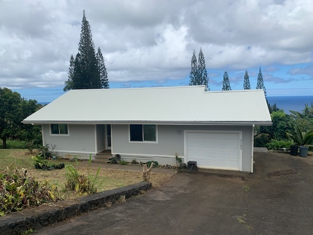 single story home with a garage and a water view