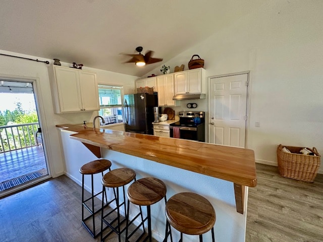 kitchen with wooden counters, a kitchen breakfast bar, stainless steel electric range oven, and black fridge