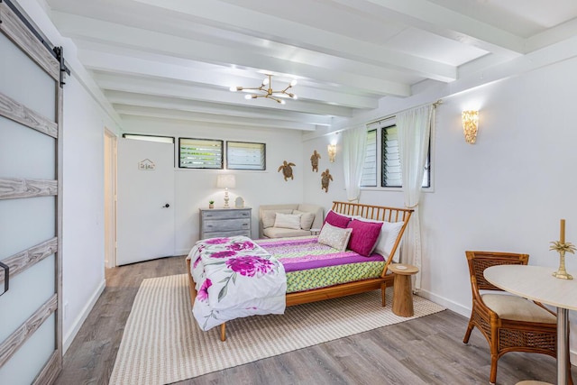 bedroom with a barn door, hardwood / wood-style floors, beamed ceiling, and an inviting chandelier