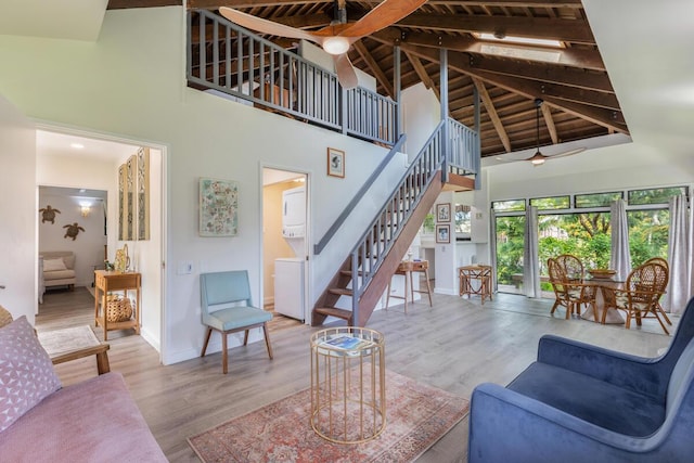 living room with wood-type flooring, stacked washing maching and dryer, high vaulted ceiling, and wood ceiling