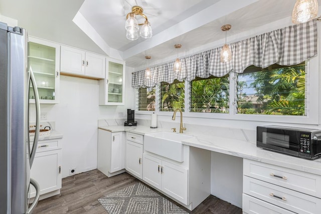 kitchen with white cabinetry, stainless steel fridge, sink, and hanging light fixtures