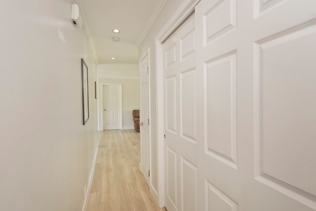 hall with light hardwood / wood-style floors and crown molding