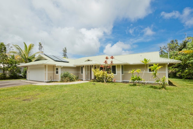 ranch-style house featuring a garage, solar panels, and a front lawn