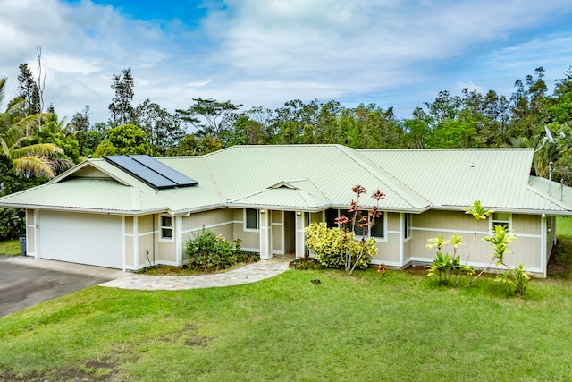 ranch-style home with a front yard, a garage, and solar panels