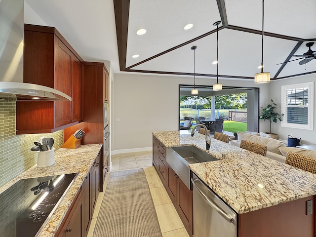 kitchen featuring appliances with stainless steel finishes, sink, wall chimney range hood, hanging light fixtures, and an island with sink