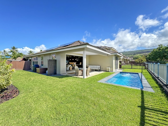 rear view of property featuring outdoor lounge area, solar panels, a lawn, a fenced in pool, and a patio area