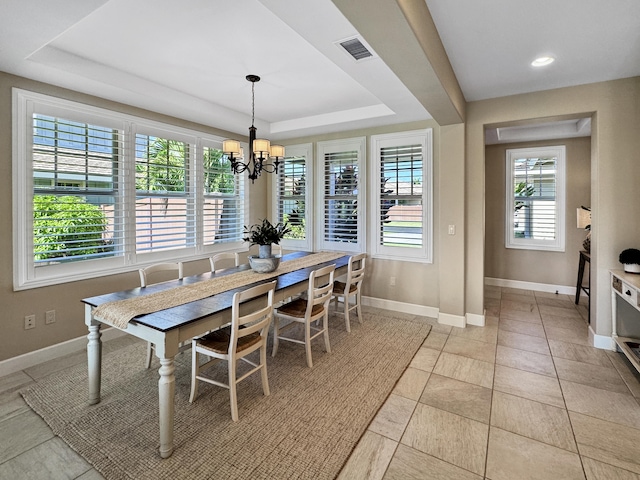 tiled dining space featuring a raised ceiling and a notable chandelier