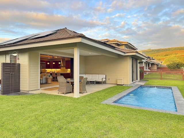 back of house featuring a fenced in pool, a patio area, a yard, and solar panels