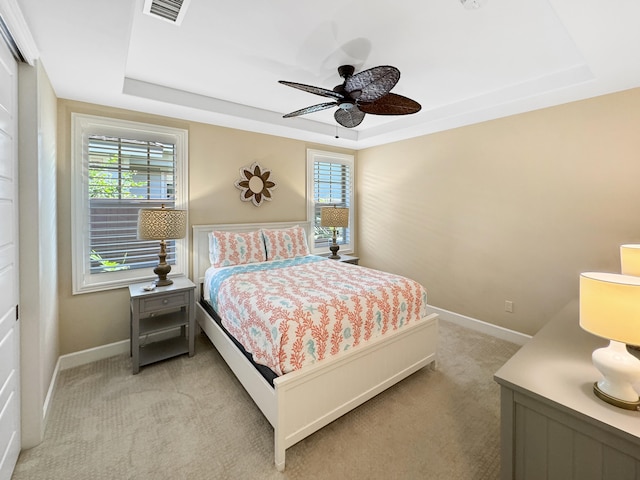 carpeted bedroom featuring a tray ceiling and ceiling fan