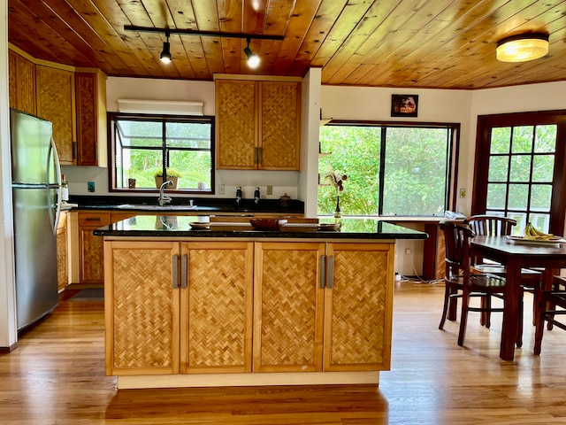 kitchen featuring track lighting, a center island, plenty of natural light, and stainless steel refrigerator