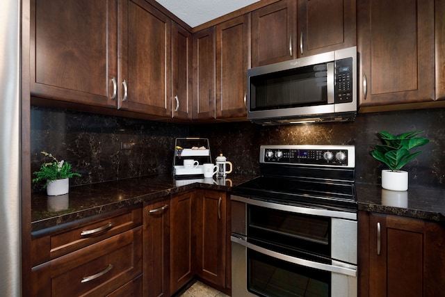 kitchen featuring dark brown cabinetry, appliances with stainless steel finishes, tasteful backsplash, and dark stone counters