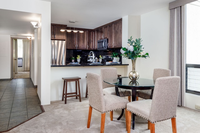 dining room with light carpet, sink, and a healthy amount of sunlight