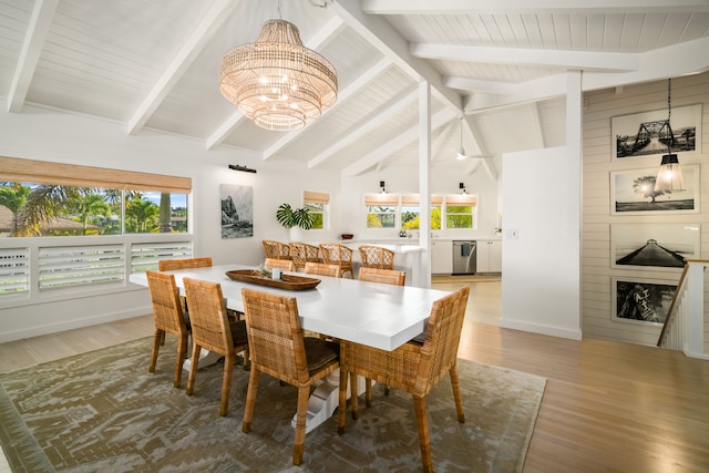 dining space with a healthy amount of sunlight, a notable chandelier, hardwood / wood-style floors, and vaulted ceiling with beams