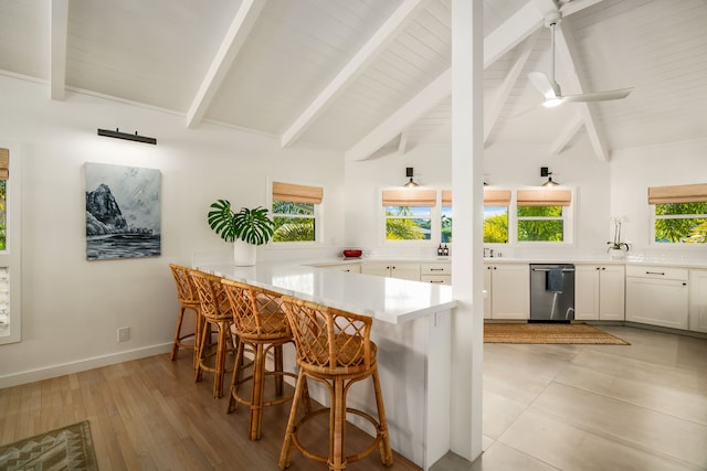 kitchen featuring dishwasher, light wood-type flooring, kitchen peninsula, ceiling fan, and a breakfast bar