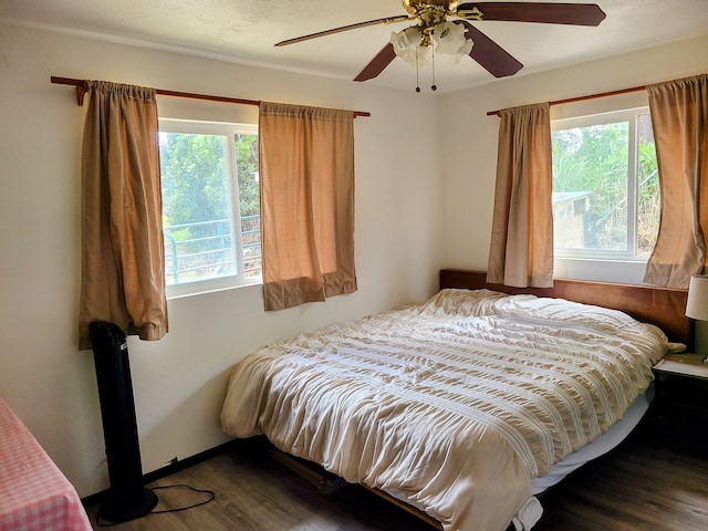 bedroom featuring dark wood-type flooring, multiple windows, and ceiling fan