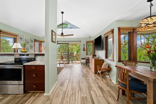 kitchen with electric stove, hanging light fixtures, light hardwood / wood-style flooring, and light stone countertops