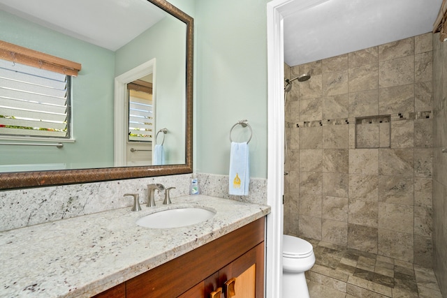 bathroom featuring tiled shower, vanity, and toilet