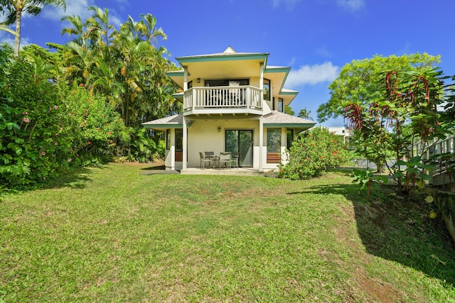 back of house featuring a lawn, a balcony, and a patio area