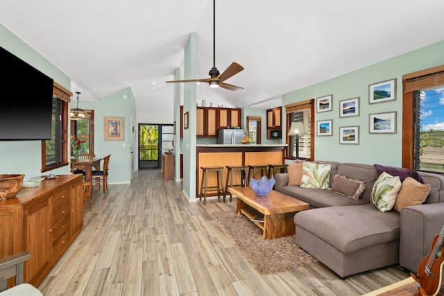 living room with ceiling fan, vaulted ceiling, and light wood-type flooring