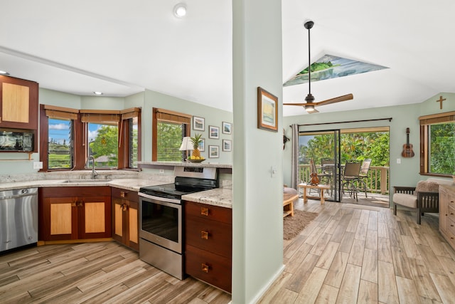 kitchen featuring sink, hanging light fixtures, stainless steel appliances, light stone counters, and light wood-type flooring