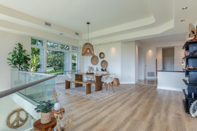 dining area featuring a raised ceiling and light wood-type flooring