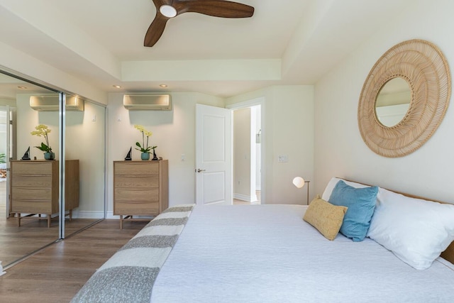 bedroom featuring dark hardwood / wood-style flooring, a closet, a tray ceiling, and an AC wall unit