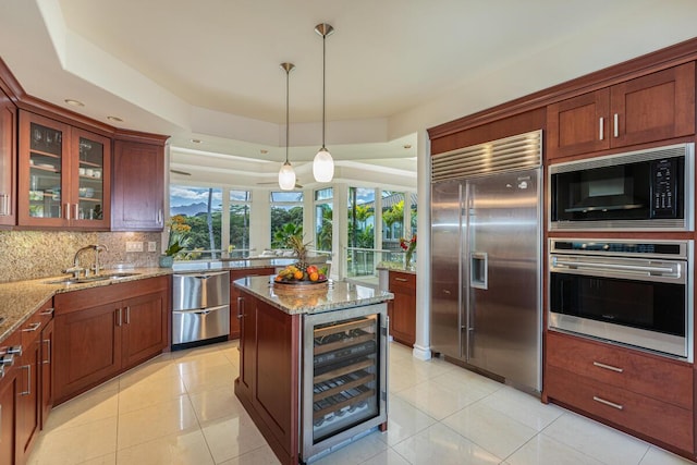 kitchen with sink, built in appliances, light stone countertops, decorative backsplash, and beverage cooler