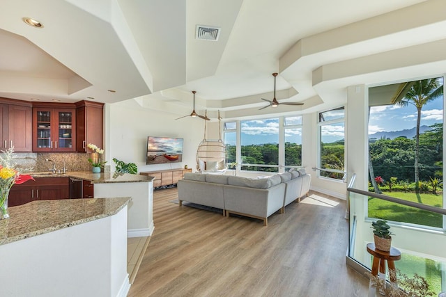 living room featuring sink, a tray ceiling, ceiling fan, and hardwood / wood-style flooring