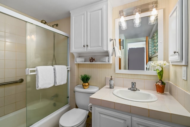 full bathroom with enclosed tub / shower combo, vanity, and toilet