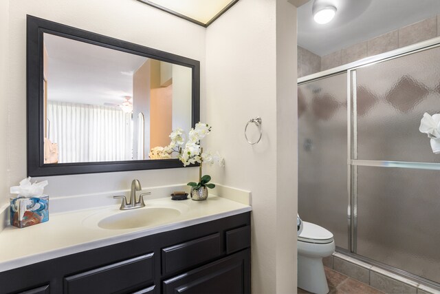 bathroom featuring vanity, a shower with shower door, toilet, and tile patterned floors