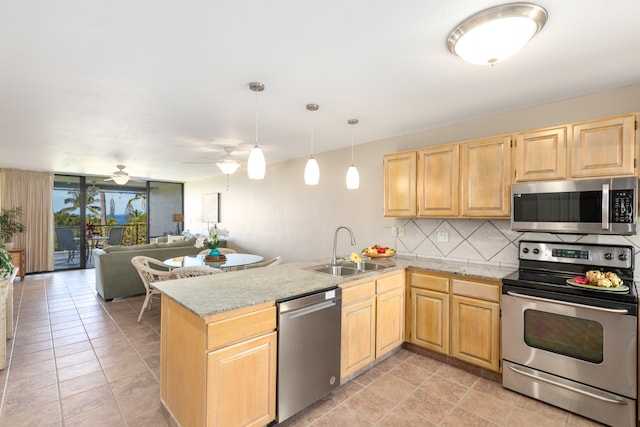 kitchen featuring stainless steel appliances, sink, kitchen peninsula, and hanging light fixtures