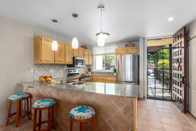 kitchen featuring pendant lighting, stainless steel appliances, kitchen peninsula, and a kitchen breakfast bar