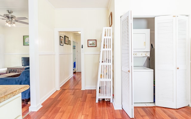 hall featuring light wood-type flooring, stacked washer / dryer, and ornamental molding