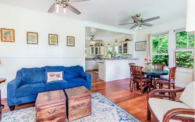 living room featuring wood-type flooring, ceiling fan, and crown molding