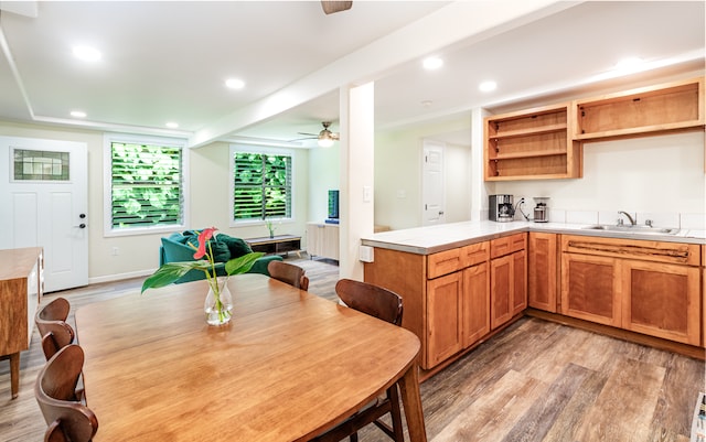 kitchen featuring ceiling fan, beamed ceiling, sink, kitchen peninsula, and light hardwood / wood-style flooring