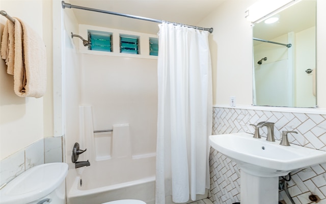 full bathroom with sink, tile walls, shower / bath combo with shower curtain, and toilet