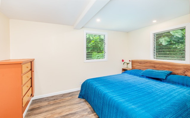 bedroom with beamed ceiling and hardwood / wood-style flooring