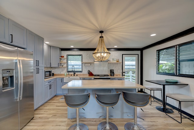 kitchen featuring pendant lighting, sink, stainless steel appliances, a notable chandelier, and light hardwood / wood-style floors