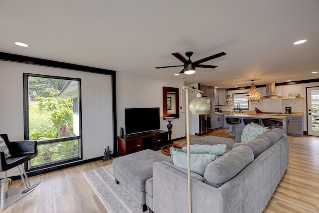 living room featuring light wood-type flooring, ceiling fan, and sink