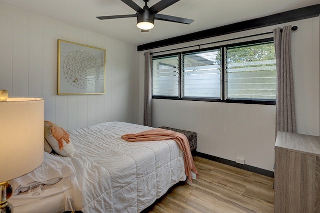 bedroom featuring wooden walls, ceiling fan, and light hardwood / wood-style flooring