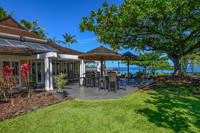 view of yard featuring french doors, a water view, and a patio