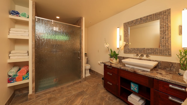 bathroom with vanity, toilet, and a shower with door